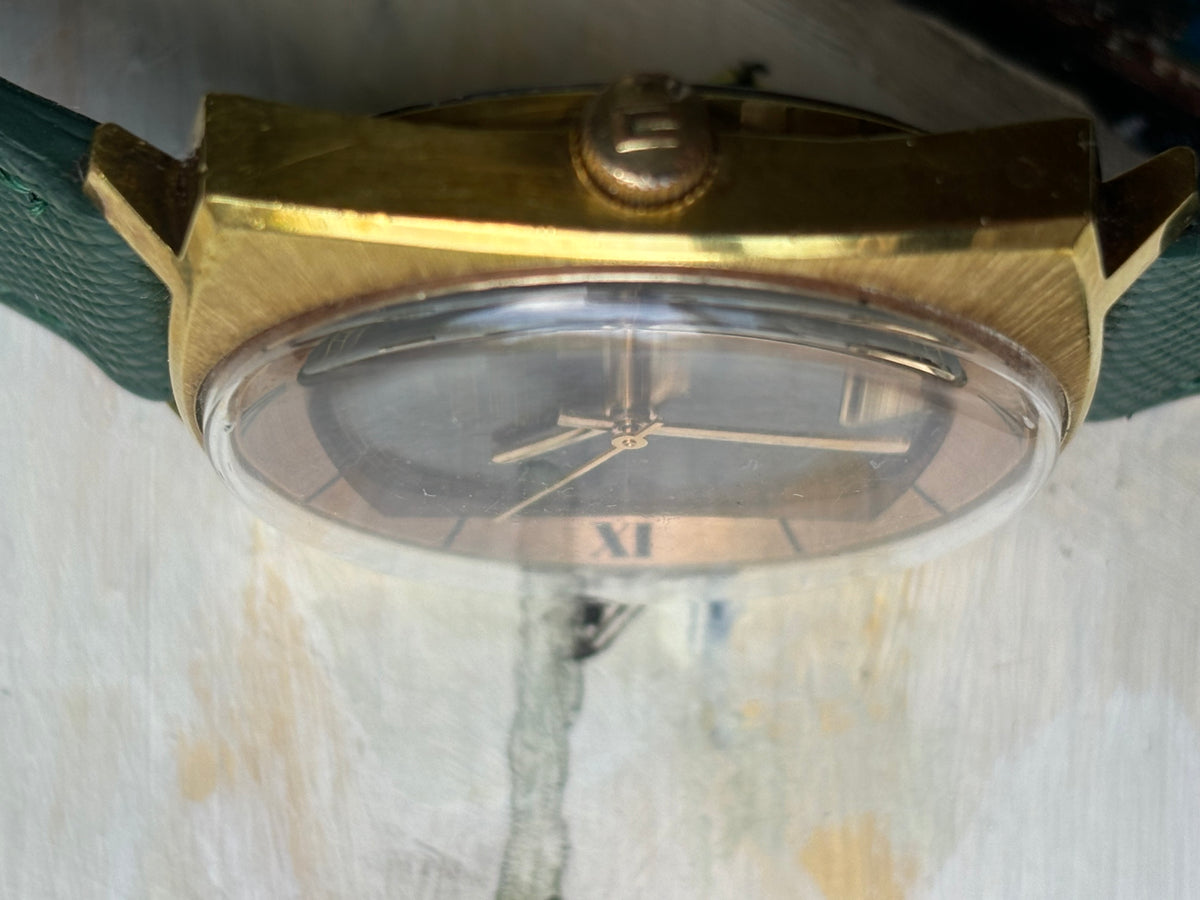 Close side view of vintage Nivada Grenchen Leonardo Da Vinci showing crown, curved crystal and gold-tone case