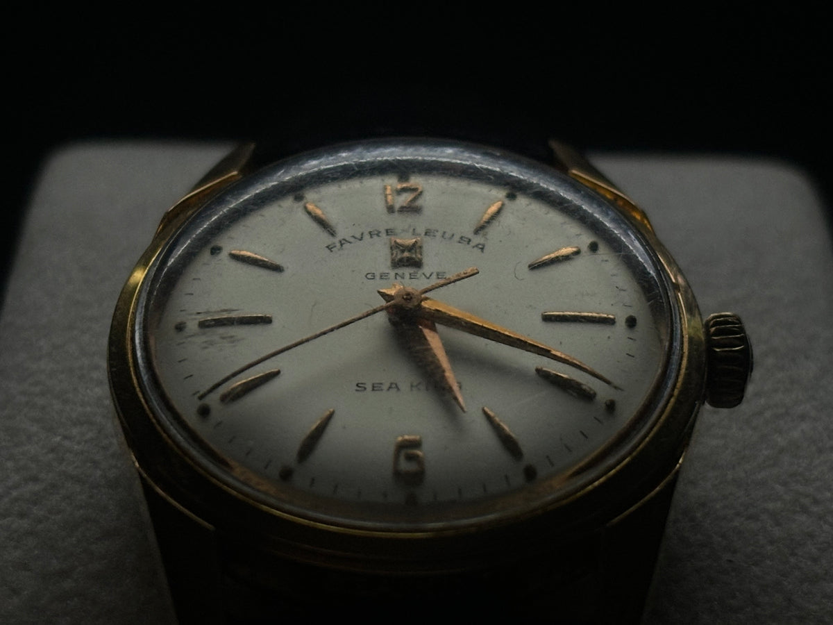 Studio front close-up of the silver dial, Arabic 12 and 6 numerals, and gold markers on the Favre-Leuba Genève Sea King.