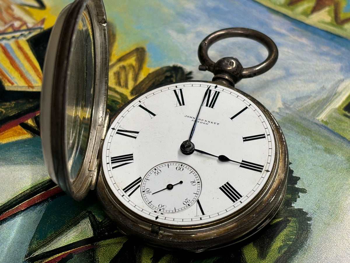 Open antique John Bennett London pocket watch showing its white dial, Roman numerals and small seconds.