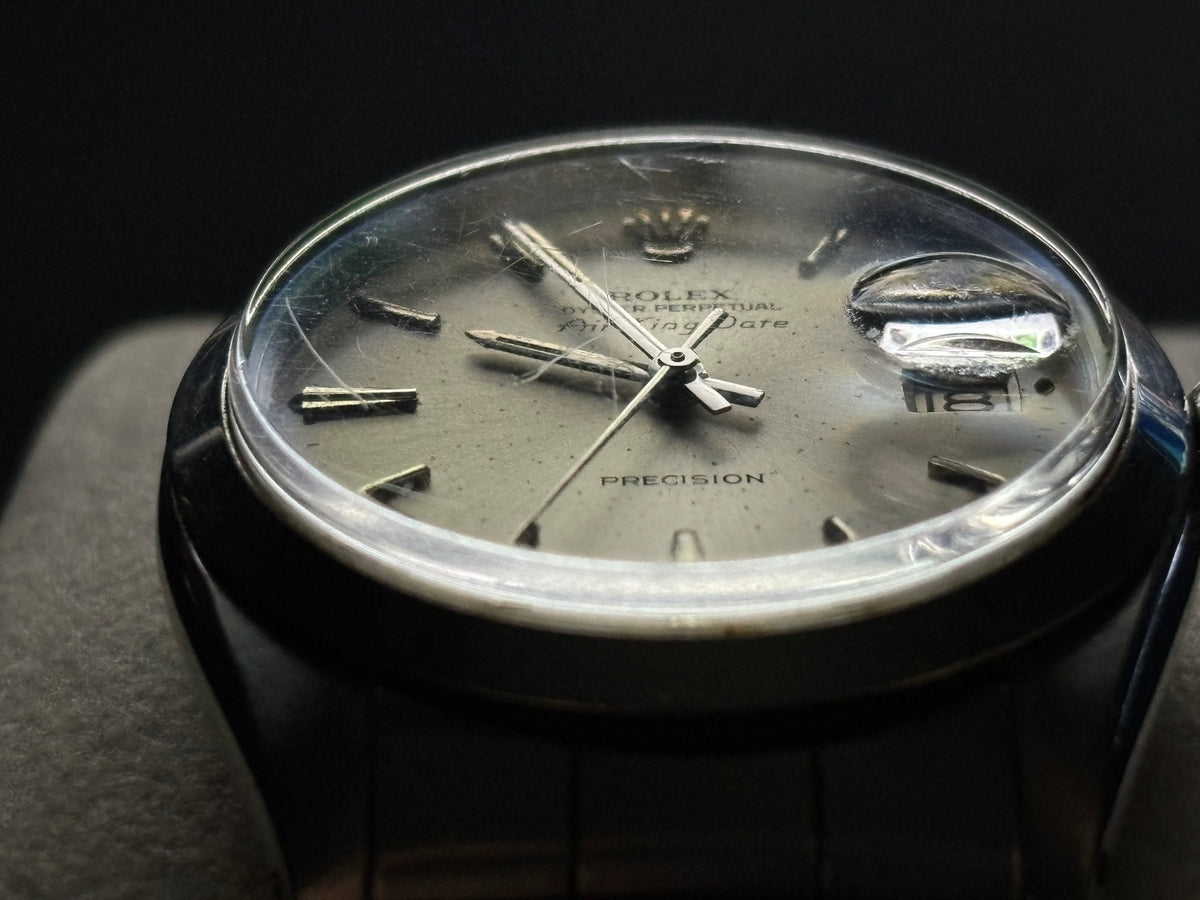 Macro view of Rolex Air-King-Date Precision ref. 5700 silver sunburst dial, acrylic crystal and Cyclops lens
