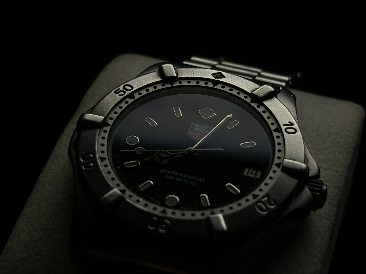 Low-light side view of a vintage TAG Heuer Professional 200 Metres stainless-steel watch.