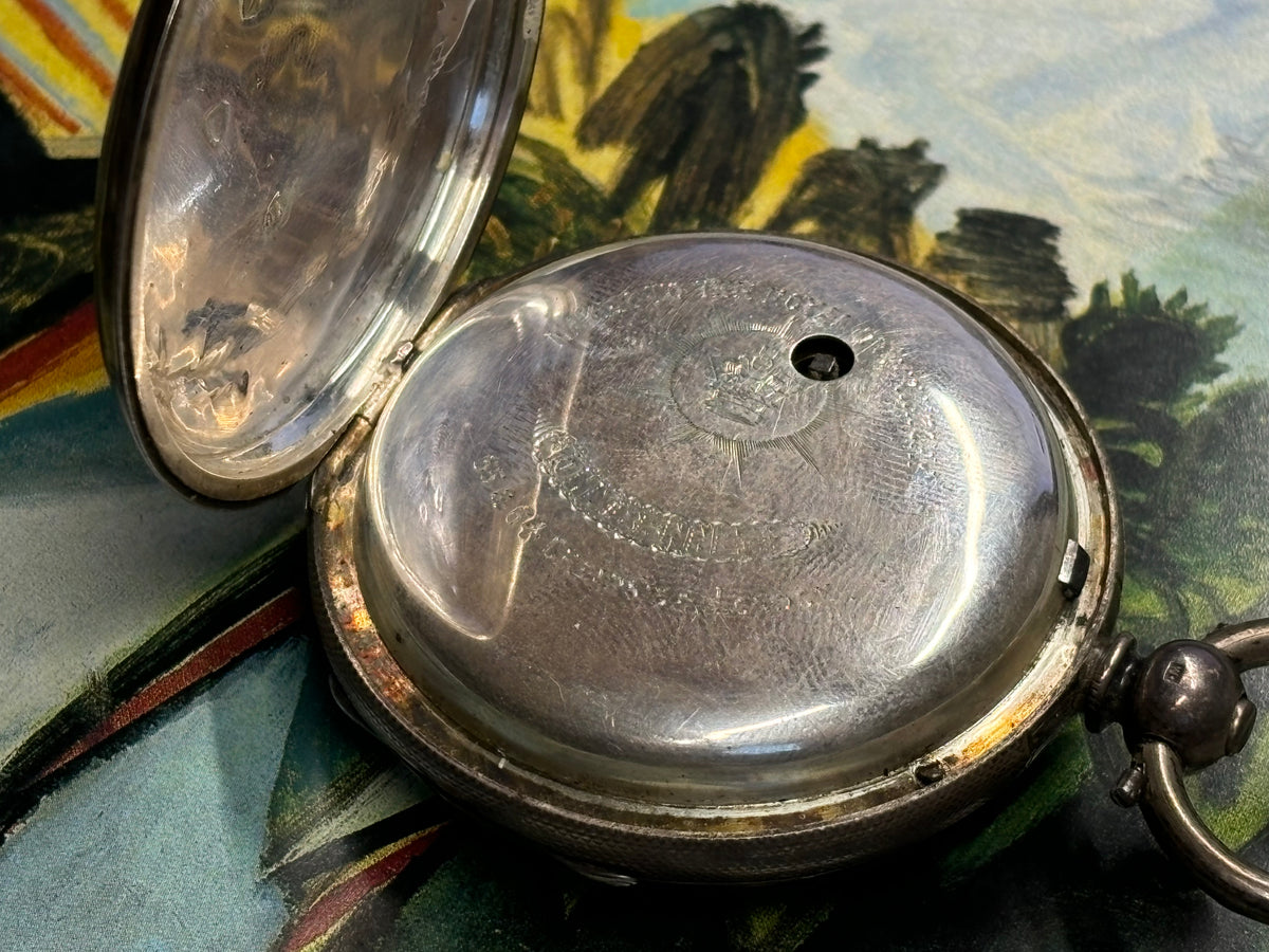 Inner case of an antique John Bennett London pocket watch with engraved maker details.