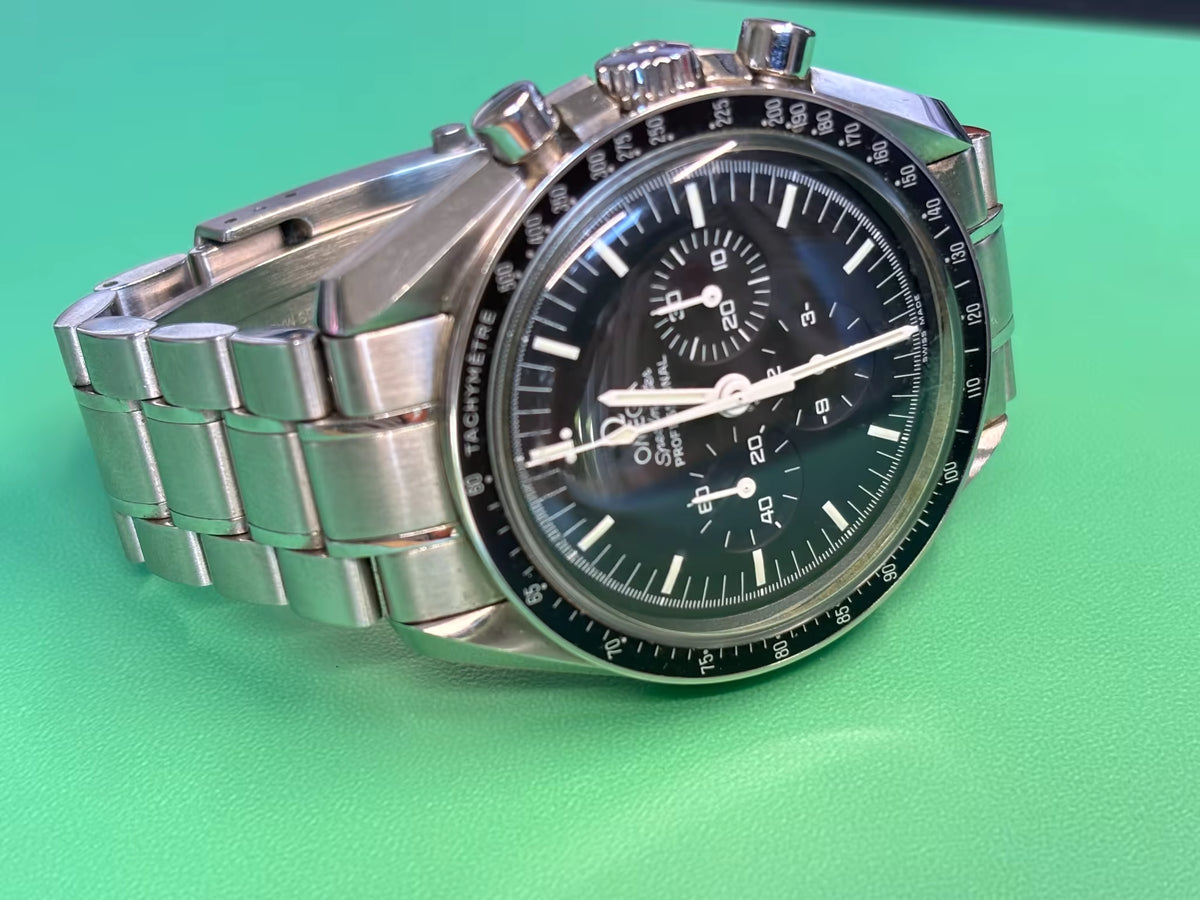 Angled view of an Omega Speedmaster Professional Moonwatch showing its black chronograph dial and bracelet.