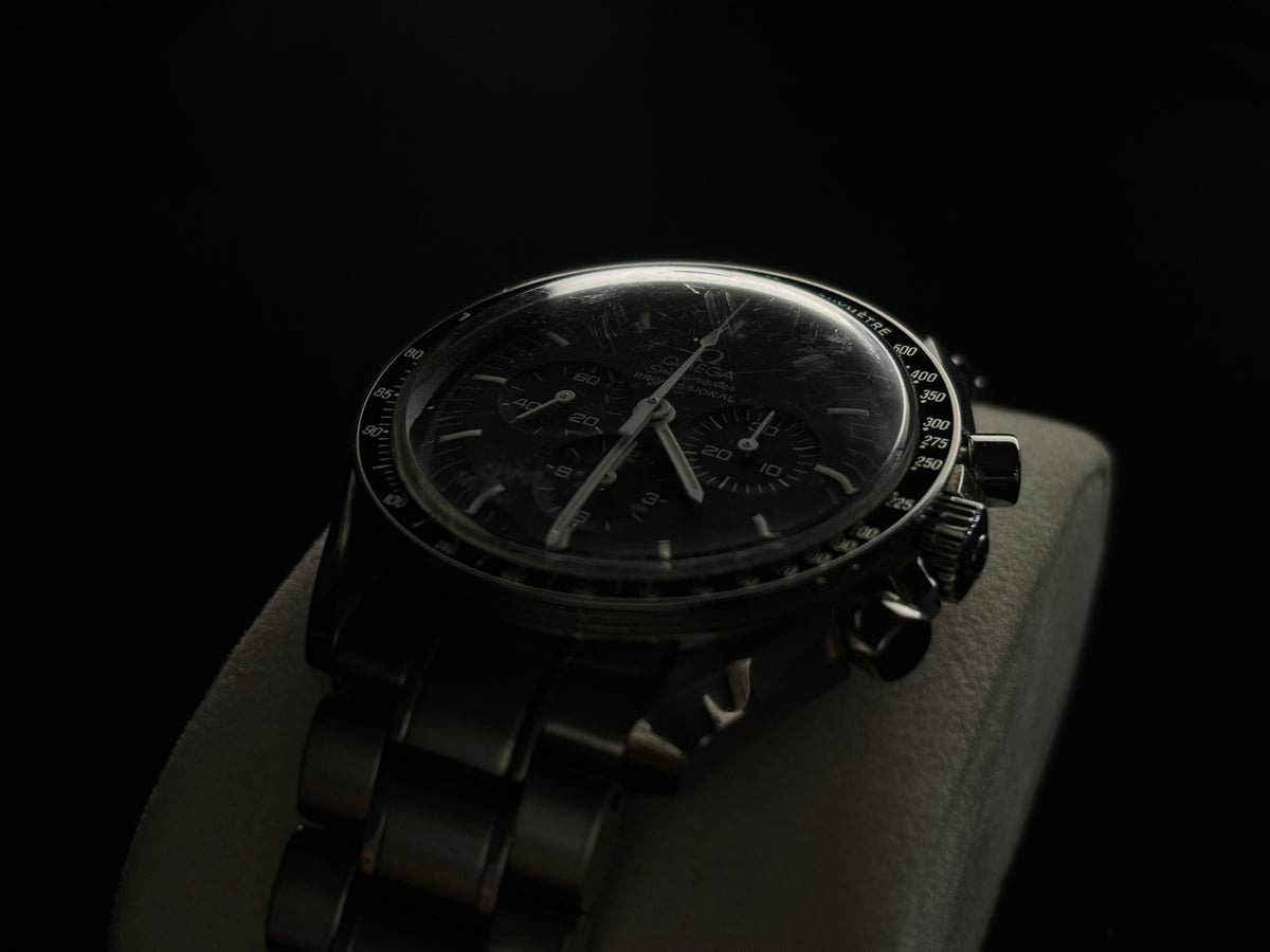 Studio angled view of an Omega Speedmaster Professional Moonwatch on its stainless-steel bracelet.