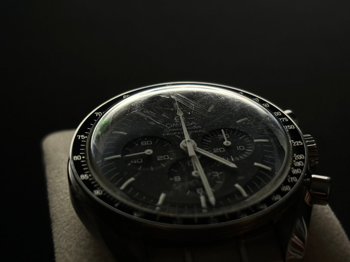 Low-light three-quarter view of an Omega Speedmaster Professional Moonwatch chronograph.