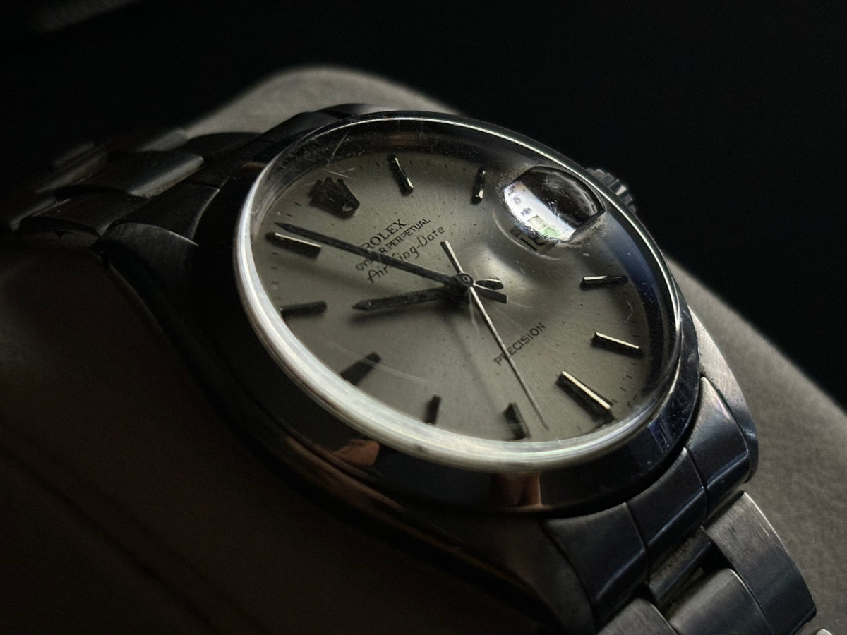 Close-up of Rolex Air-King-Date Precision ref. 5700 silver sunburst dial, acrylic crystal and Cyclops lens