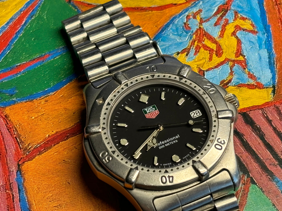 Close-up of a vintage TAG Heuer Professional 200 Metres black dial and stainless-steel bezel.